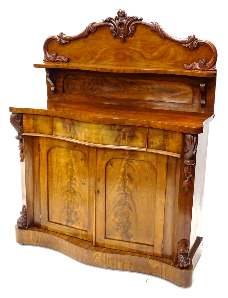 A Victorian mahogany chiffonier, the raised back carved with scrolls and with a shaped shelf, the