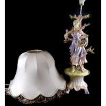 A Continental pottery table lamp, modelled in the form of a lady with basket of flowers etc., on a