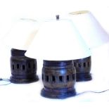 A set of three African carved hardwood table lamps, each of circular form with pierced sections to