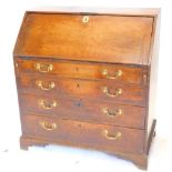 A George III oak bureau, the fall enclosing a fitted interior over four graduated drawers, with