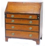 An early 19thC oak and mahogany cross banded bureau, the fall enclosing a fitted interior above four