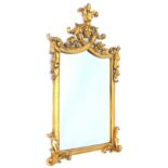 A gilt wall mirror, the frame decorated with leaves, scrolls etc., 99cm H, 60cm W.