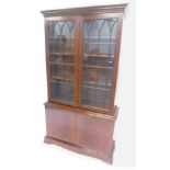 A mahogany bookcase in George III style, the top with two glazed doors, the base with a slide and