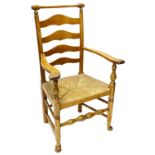 A 19thC ash ladder back chair, with a turned rail, shaped arms and rush seat with turned tapering