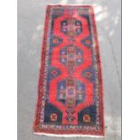 A Hamadan runner, with a central multi coloured pole medallion on a red and blue ground, with