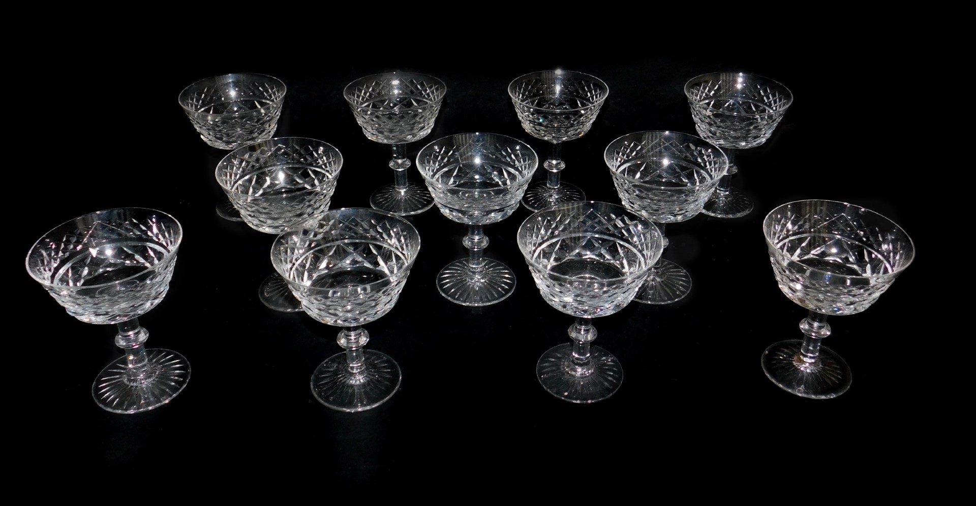 A set of eleven cut glass champagne cups, raised on a single knopped stem, on a conical foot.