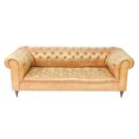 A Victorian style Chesterfield sofa, upholstered in button back tan leather, raised on turned oak