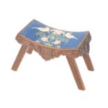 A Victorian oak stool, the curved seat with brass studded tapestry decorated with birds and flowers,