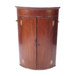 A George III mahogany bow front hanging corner cabinet, with ebony line inlay, two doors opening