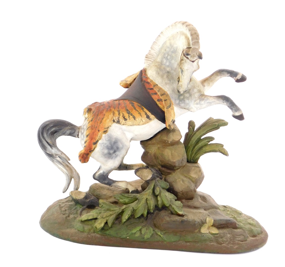 An early 20thC cold painted lead figure of a prancing horse, draped in a tiger skin, on a