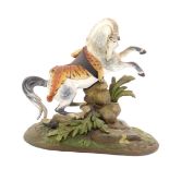 An early 20thC cold painted lead figure of a prancing horse, draped in a tiger skin, on a