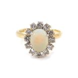 An 18ct gold opal and diamond ring, the opal set in a surround of twelve brilliant cut diamonds,