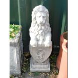 A concrete garden figure of a lion, modelled rampant holding an armorial shield, on a step square