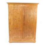 A pine double wardrobe, the outswept pediment over a pair of doors, raised on a bracket foot base,