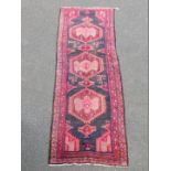 An Azari runner, with a central pole medallion in pink, on a black ground with two wide borders,