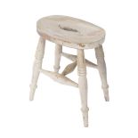 A late 19thC white painted beech blacksmith's stool, the oval seat raised on turned legs, united