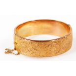 A 9ct rose gold hinged bangle, with foliate engraving, 1919, 22.2g.