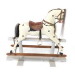 A spotted white rocking horse, on a grey painted stand, with saddle stirrups and reins, 103cm H,