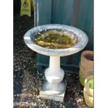 A reconstituted stone bird bath, with circular top raised on a baluster stem, on a square plinth,