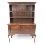 A Victorian oak dresser, the plate rack with outswept pediment over a central stained glass door,