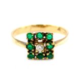 A 9ct gold emerald and diamond ring, set with a central diamond in a surround of eight emeralds,