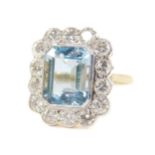 An 18ct gold aquamarine and diamond ring, the rectangular cut aquamarine in a surround of
