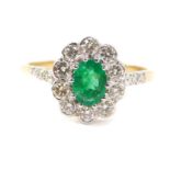 An 18ct gold emerald and diamond ring, the oval cut emerald in a surround of diamonds, with