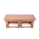 A Reprodux oak nest of tables, comprising one long table and two small slot in tables, raised on