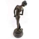 A bronze figure modelled as a classical naked lady, raised on a base with masks and balls, signed