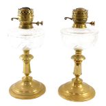 A pair of duplex brass oil lamps, with cut glass reservoirs, raised on a turned and octagonal