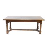 A 17thC style oak refectory table, the three plank top raised on turned legs united by a shaped