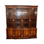 A Reprodux Georgian style mahogany breakfront bookcase, the dental moulded outswept pediment over