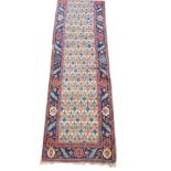 A Turkish runner, decorated with red and blue repeating floral motifs against cream ground, within a
