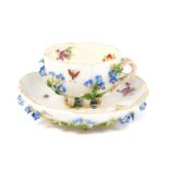 A 19thC Dresden porcelain miniature tea cup and saucer, painted and encrusted with flowers,