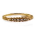 A Victorian 15ct gold sapphire and diamond bangle, channel set on a snap clasp with safety chain