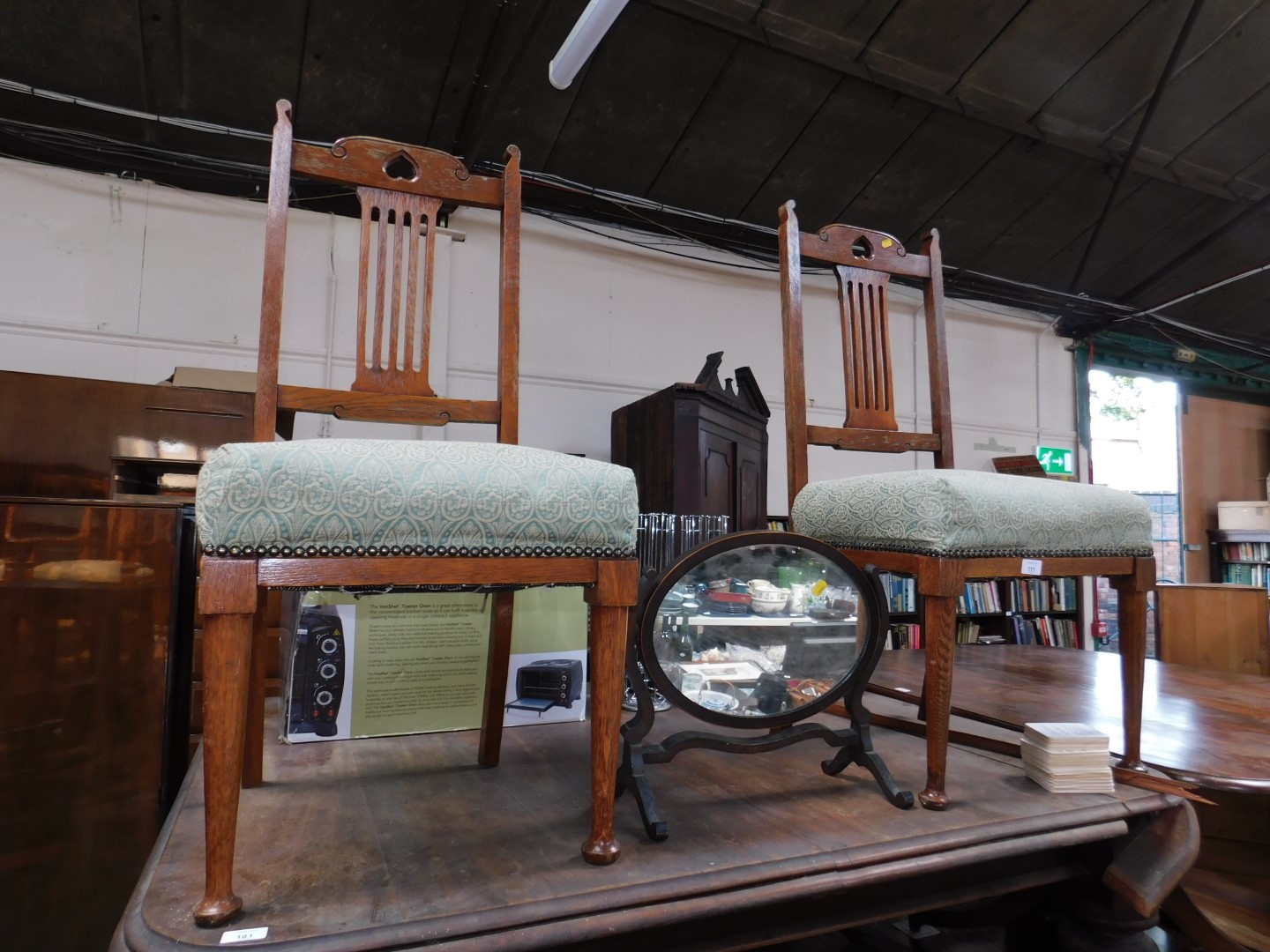 An Edwardian oval swing framed toilet mirror, and a pair of Arts & Crafts hall chair. (3)