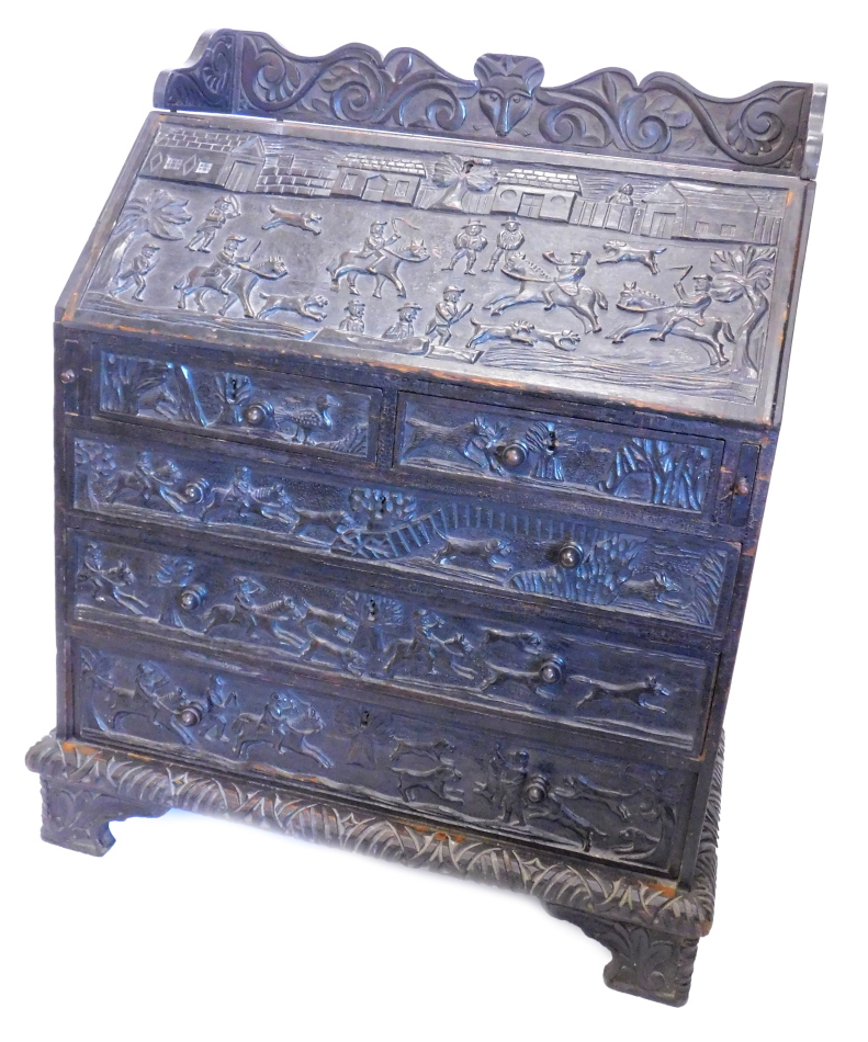 A 19thC oak bureau, carved overall with hunting scenes, fox, masks, scrolls etc., the top with a