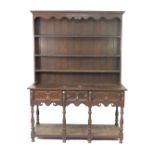 A Victorian oak dresser, the plate rack with outswept pediment over three shelves, above three