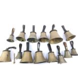 Fourteen hand bells by W Pawson, Leeds, some with hammers, with leather handles, bearing labels from