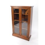 A Victorian mahogany bookcase, the pediment over two glazed doors, enclosing three shelves, raised