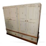 A cream painted pine quadruple wardrobe, with four double panelled doors, opening to reveal two