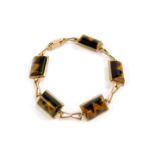 A 9ct gold and tiger's eye bracelet, with five semi cylindrical links, interspersed with bows, on
