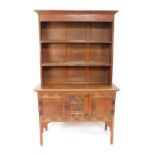 A Victorian oak dresser, the outswept pediment over a two shelf plate rack, above three carved