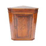 A George III oak and mahogany cross banded hanging corner cupboard, the door with shell paterae,
