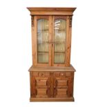 A Victorian style pine cupboard bookcase, marriage, the outswept pediment over two glazed doors