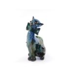 A C H Brannam Barum pottery figure of a novelty cat, modelled seated with a bow around its neck, its