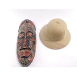 A carved tribal mask, 49cm H, together with a pith helmet. (2)