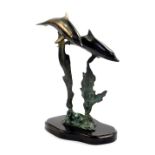 A copper sculpture modelled as two dolphins, swimming on a seaweed support, on a shaped base, 27cm