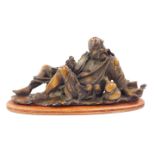 A Chinese resin figure modelled as Li Tieguai, The Diseases Beggar, modelled recumbent, on an oval