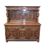 A Victorian Elizabethan style oak dresser, the outswept pediment over a panelled frieze, supported